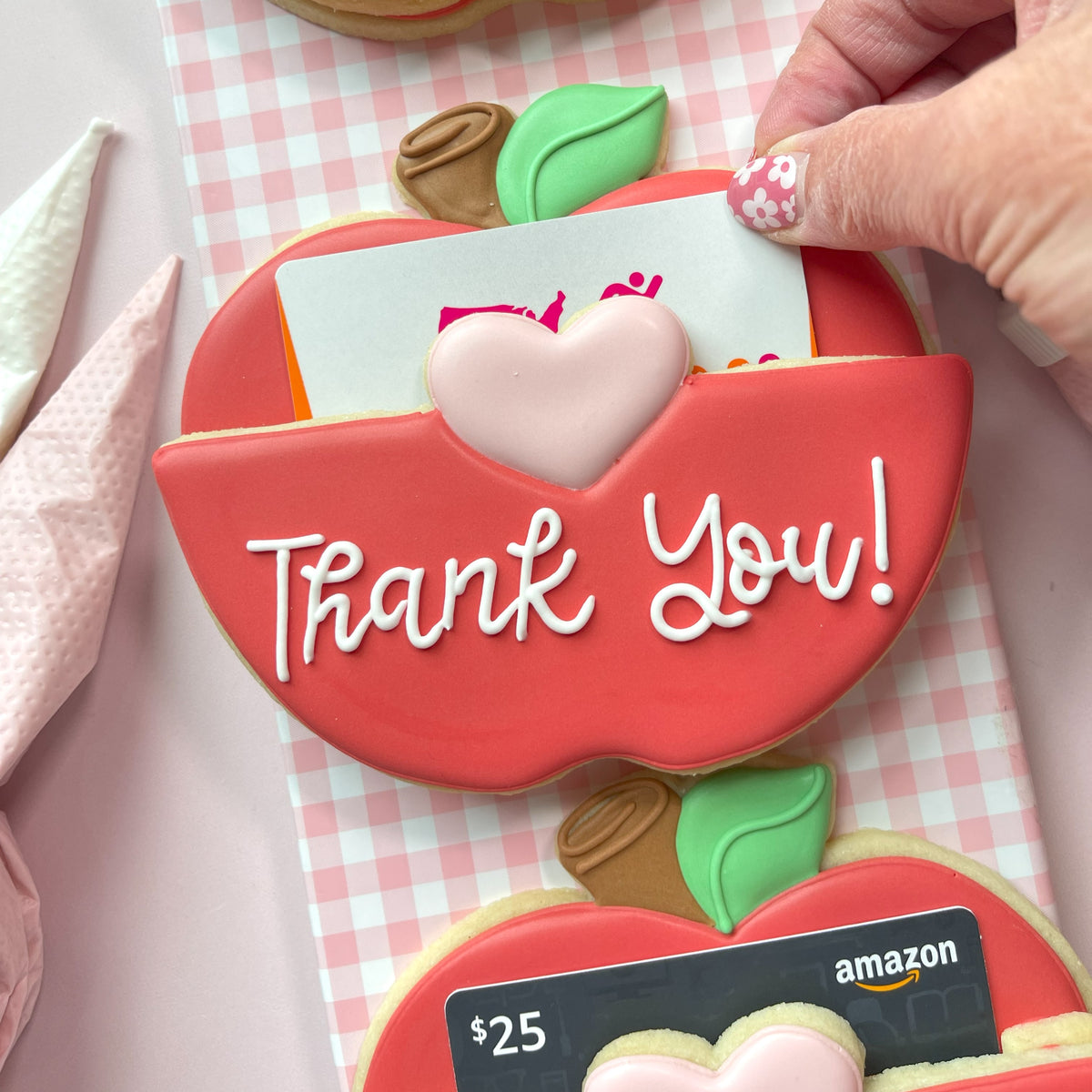 Red apple-shaped cookie with white icing thank you text and pink heart decoration from 3pc apple gift card holder cookie cutter set