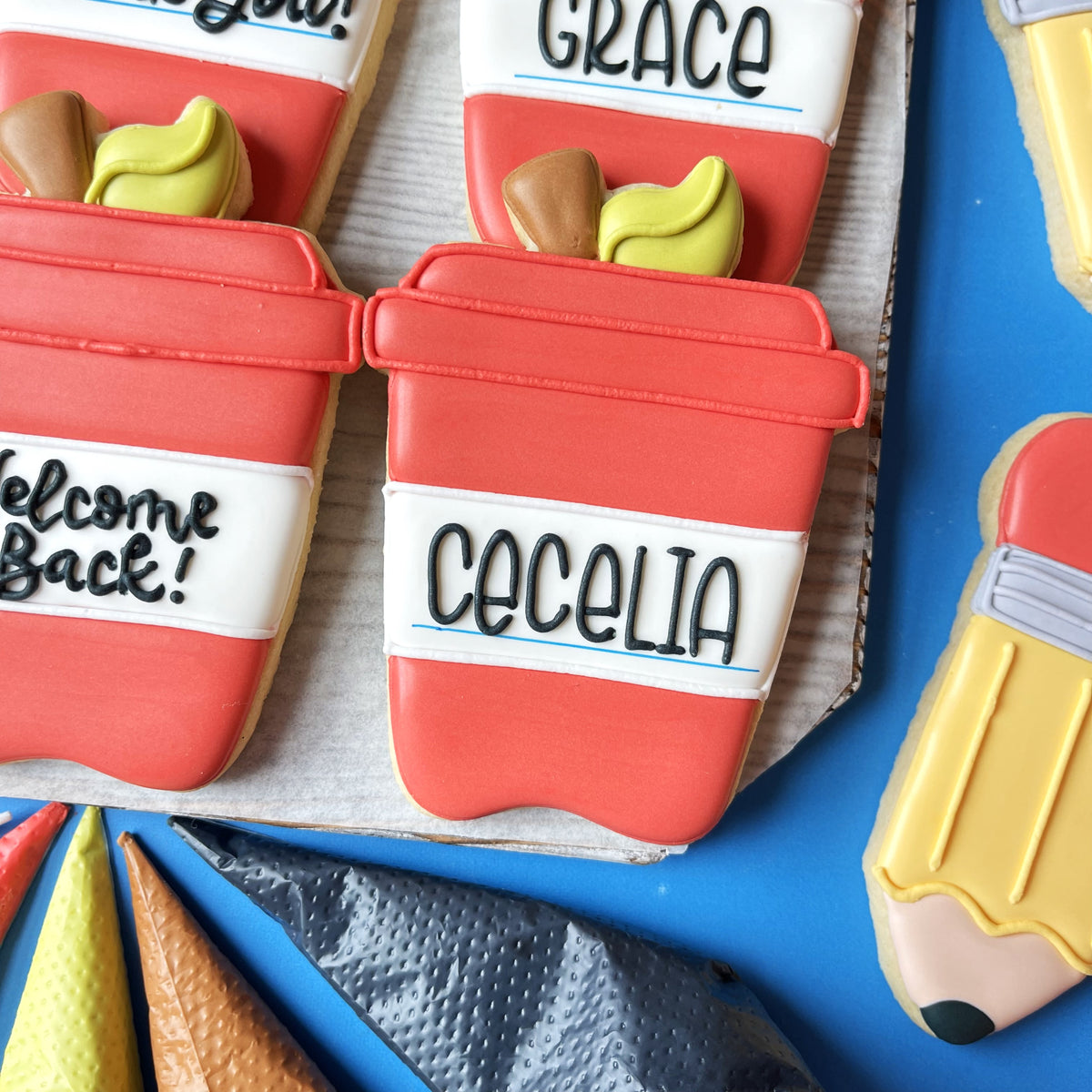 Red frosted sugar cookie shaped like a coffee cup with white icing band and black lettering made with apple latte cookie cutter