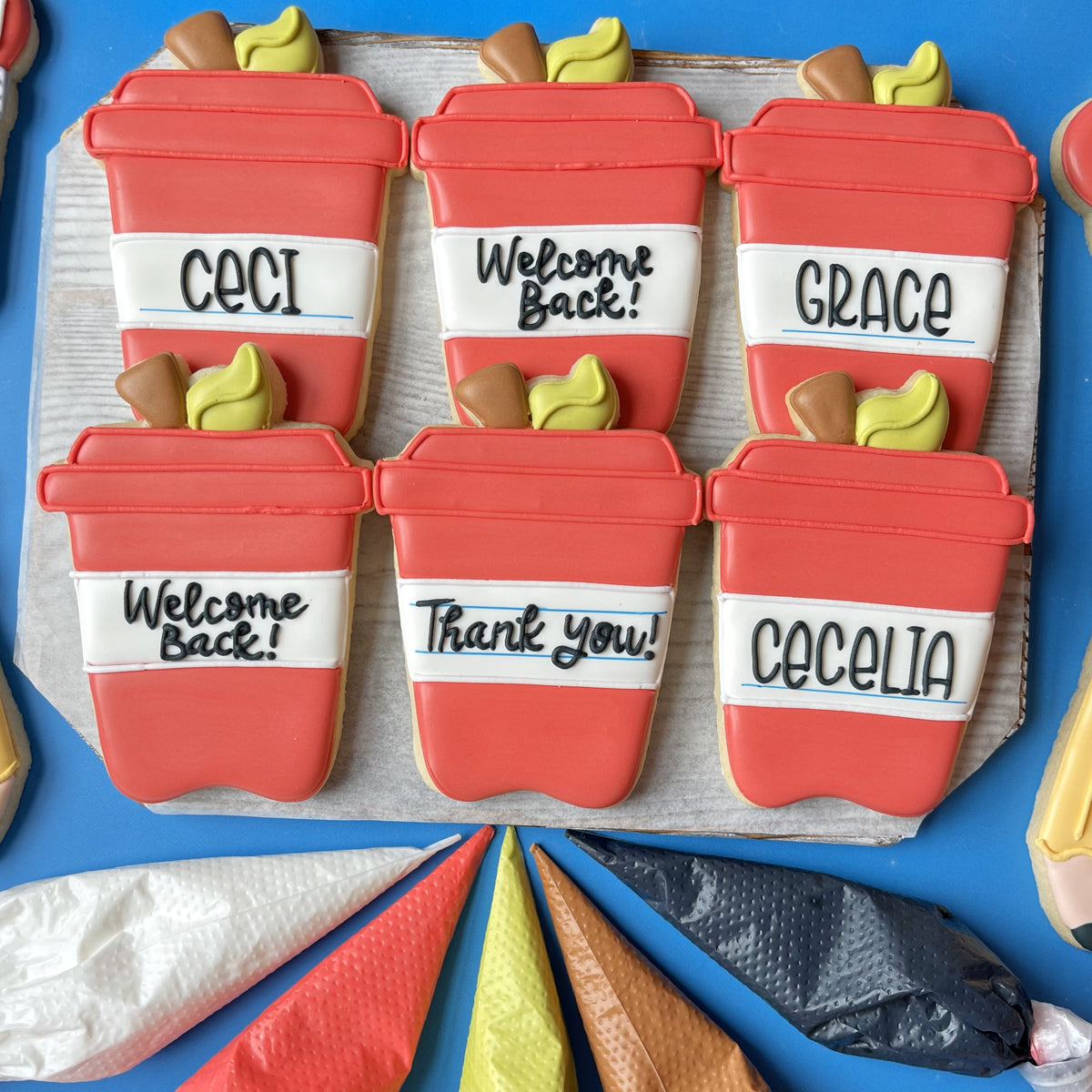 Red and white frosted sugar cookies shaped like coffee cups made with apple latte cookie cutter and personalized messages