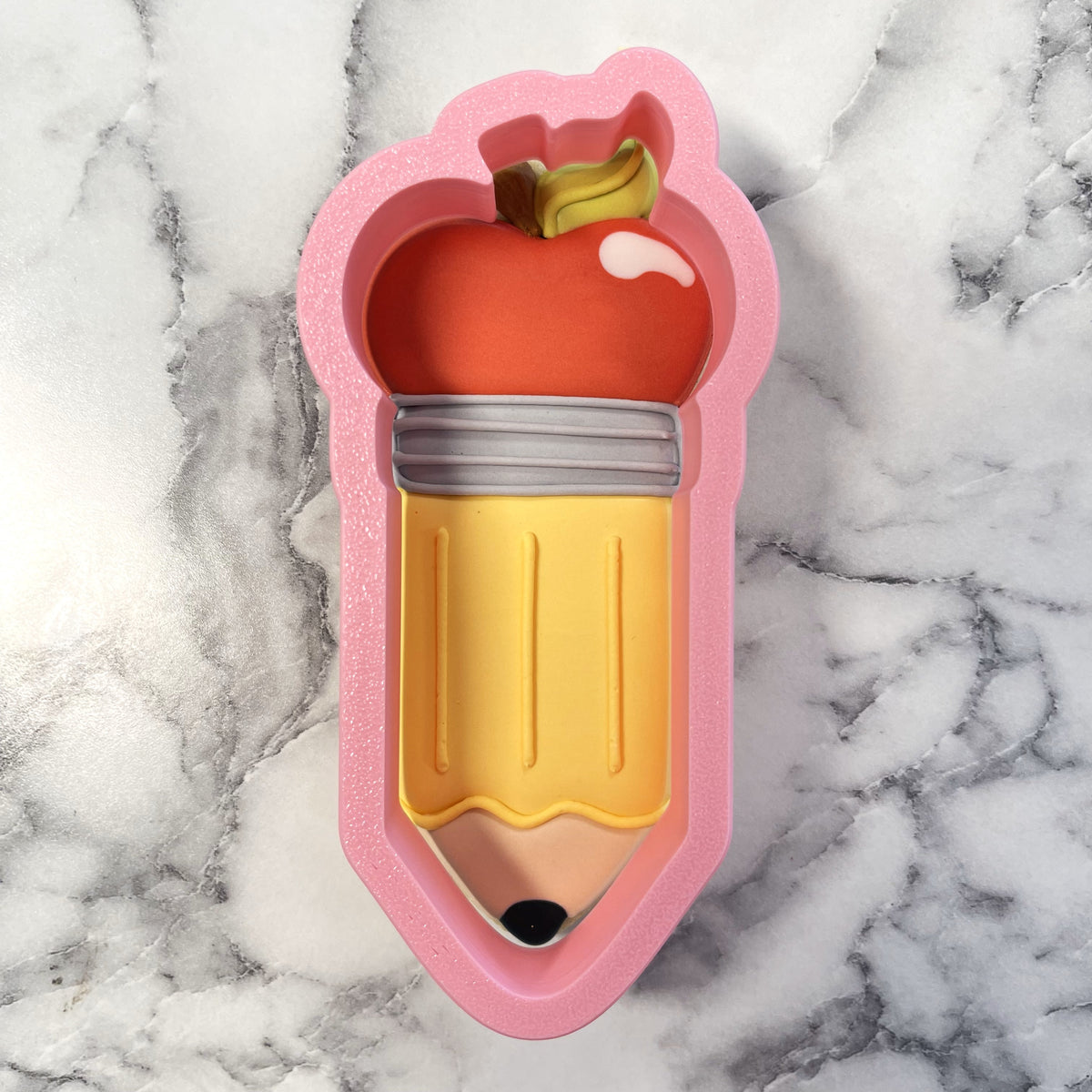 Pink silicone apple pencil cookie cutter with a yellow body and a red apple on top for baking and crafting