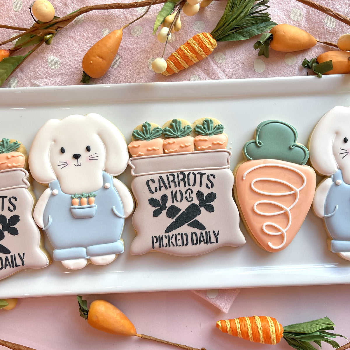 Pastel-colored sugar cookies shaped like bunnies carrot baskets and carrots with delicate icing from bunny farmer cookie cutter bundle with stencil