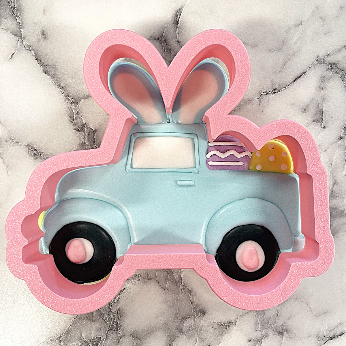 Pink bunny truck cookie cutter featuring a light blue vintage truck with black wheels and pastel eggs in the bed