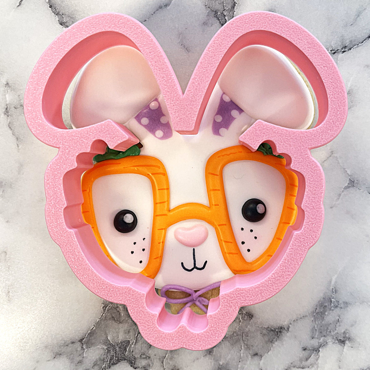 Pink bunny with carrot glasses cookie cutter featuring orange glasses purple bow tie and white face details
