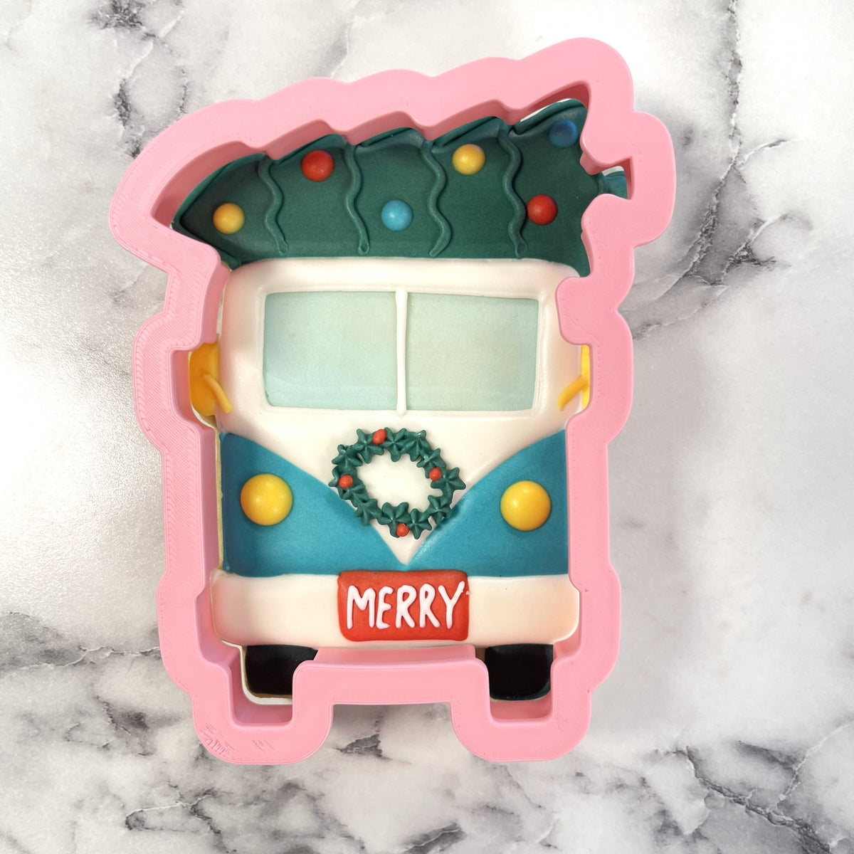 A festive pink silicone bus with tree cookie cutter shaped like a vintage volkswagen van with holiday decorations