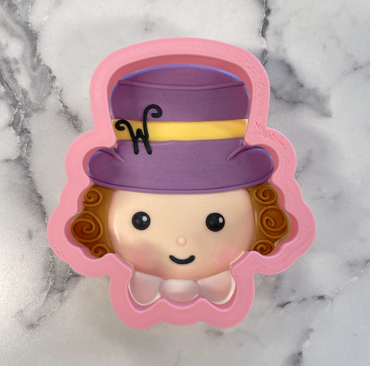 Pink silicone candy man cookie cutter shaped like a cartoon character with a purple top hat and yellow band