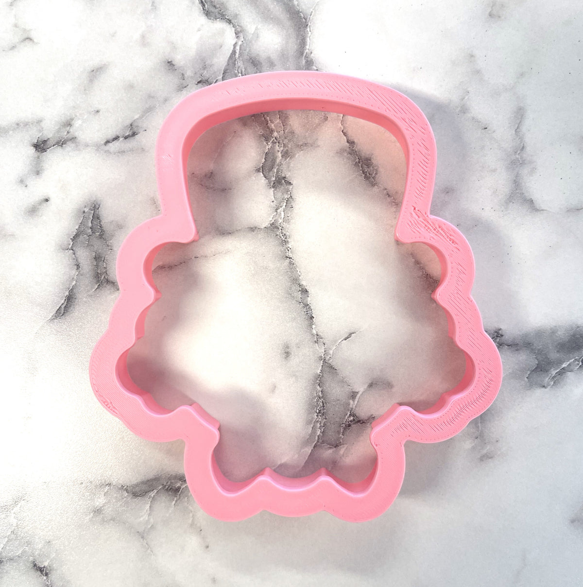Pink silicone candy man cookie cutter shaped like a cartoonish ghost with scalloped edges for baking and crafts