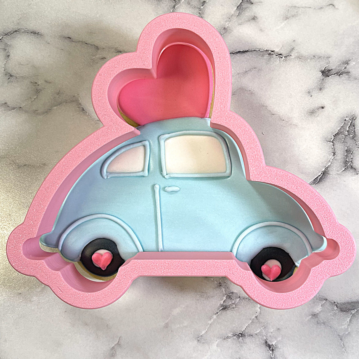 Pink silicone cake pan shaped like a light blue vintage car with heart details for car with heart cookie cutter