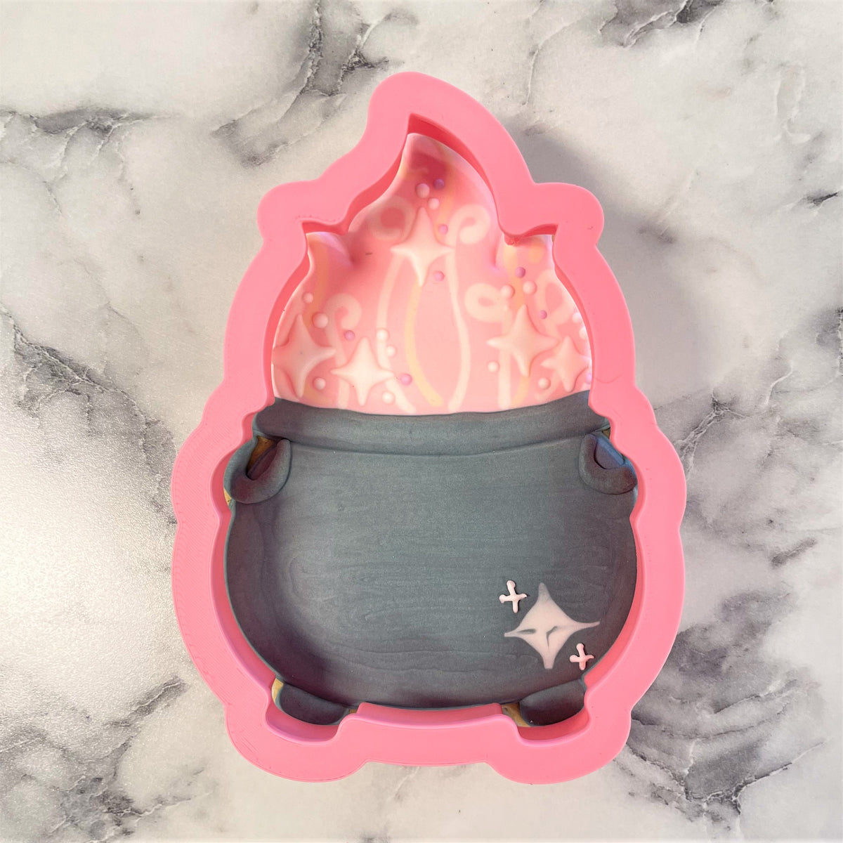 Pink silicone cauldron cookie cutter with dark gray base and sparkly pink interior for baking and crafting