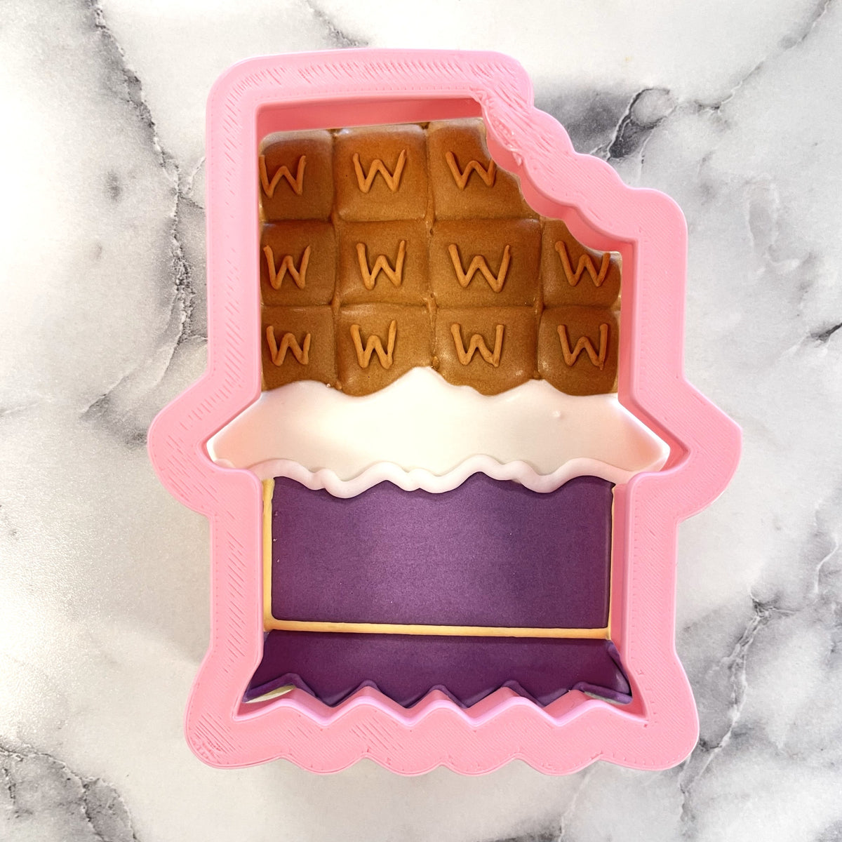 Pink silicone chocolate bar cookie cutter with brown white and purple layered design featuring w lettering