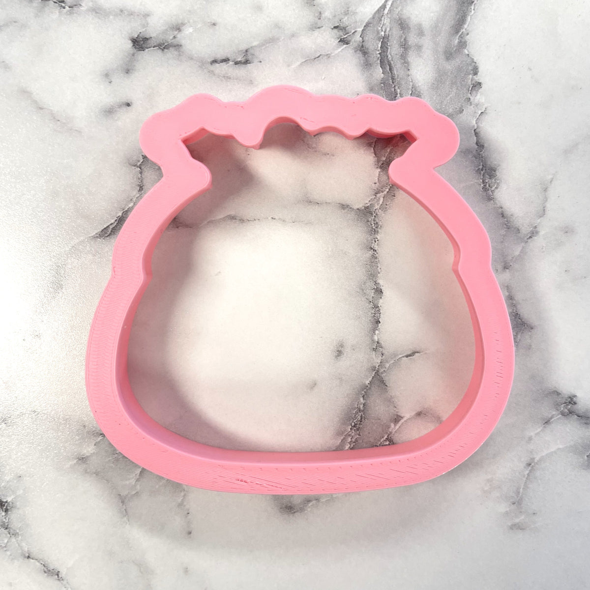 Pink silicone Christmas pudding cookie cutter shaped like a money bag for festive baking and decorating