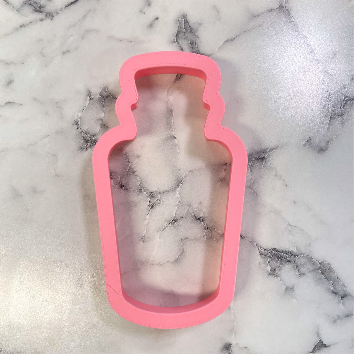 Pink silicone comic potion bottle cookie cutter for baking shaped like a bottle with detailed edges