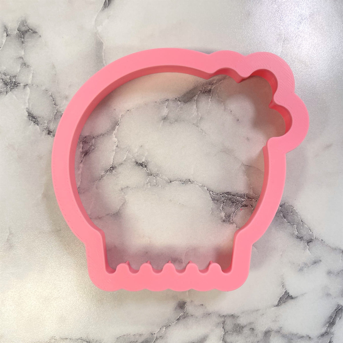 Pink silicone comic skull girl cookie cutter with smooth flexible surface and scalloped edge detailing
