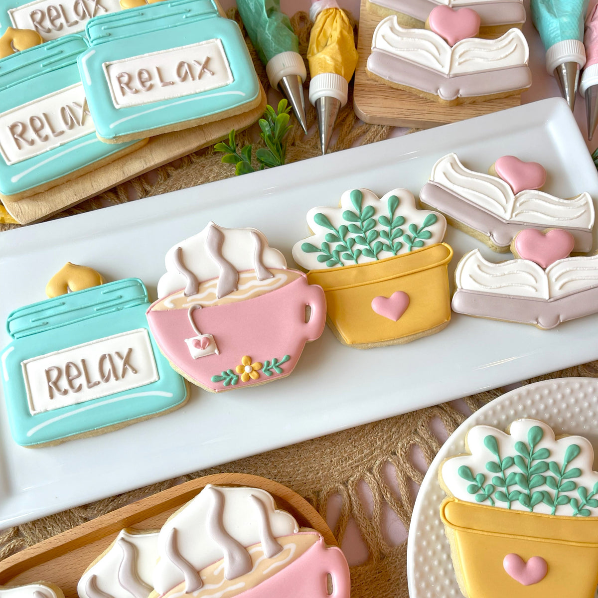 Pastel pink sugar cookie shaped like a steaming tea cup with teabag and yellow flowers made with cozy jar candle cookie cutter
