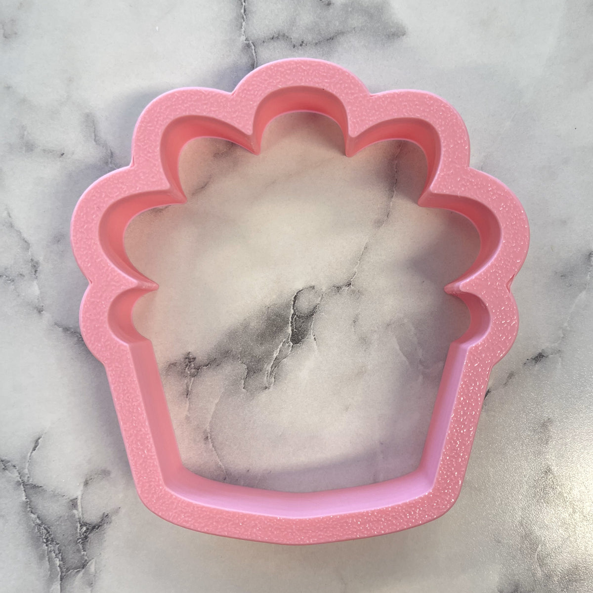 Pink glittery metal cupcake-shaped cookie cutter from cozy house plant collection for baking and decorating