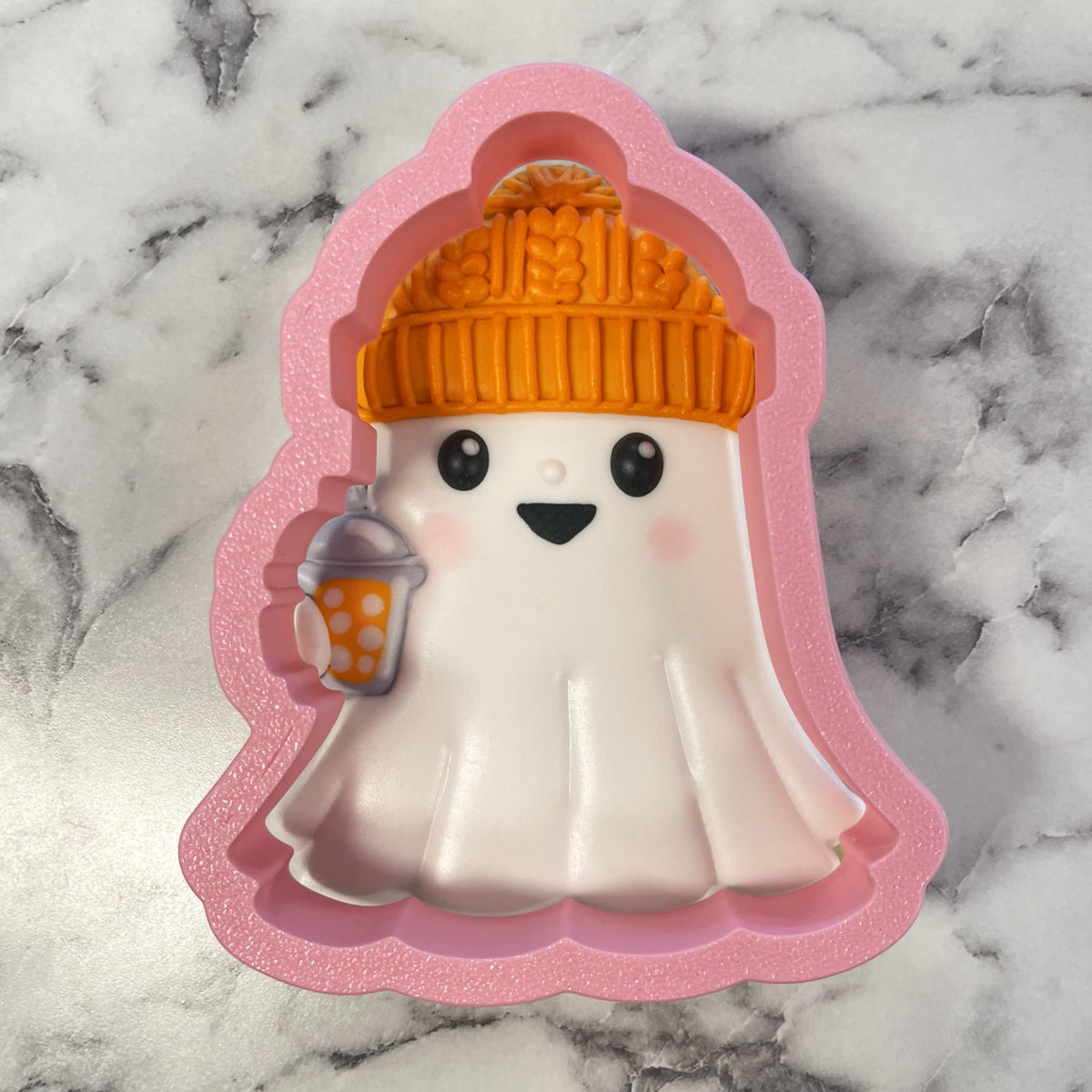 Cozy ghost cookie cutter shaped as a white ghost with an orange beanie holding a pink glitter silicone cup
