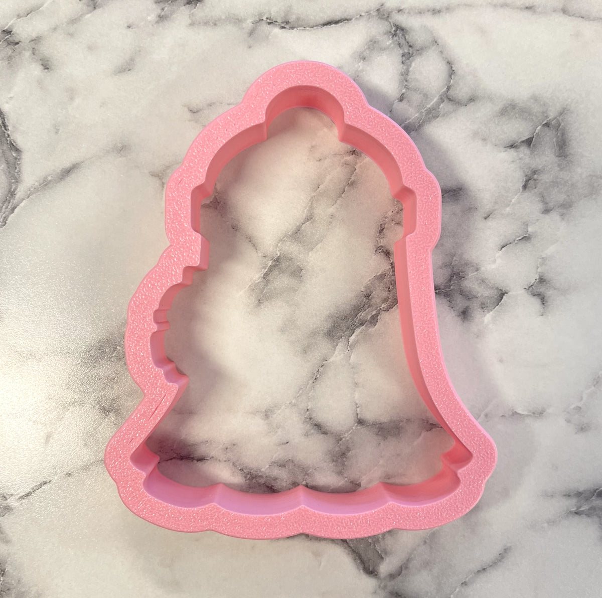 Pink bell-shaped cozy ghost cookie cutter with textured glittery finish for festive baking and decorating
