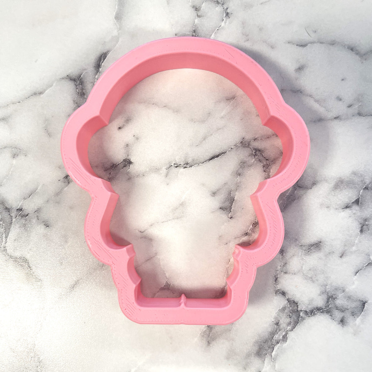 Pink silicone skull-shaped mold containing a white and gray marbled soap bar for cute astronaut cookie cutter craft