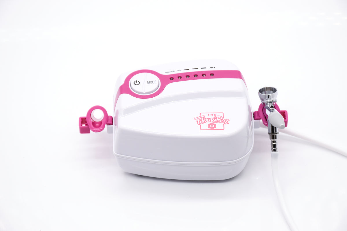 White and pink 5-speed flour box airbrush system with sleek compact design featuring the flower box logo on its side