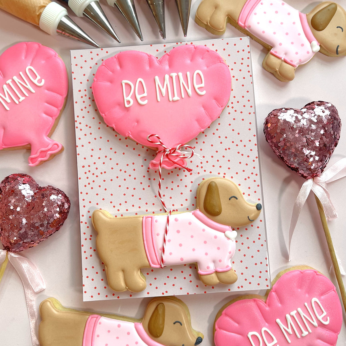Pink heart-shaped cookie with be mine icing tied to red and white string from dachshund valentine cookie cutter bundle