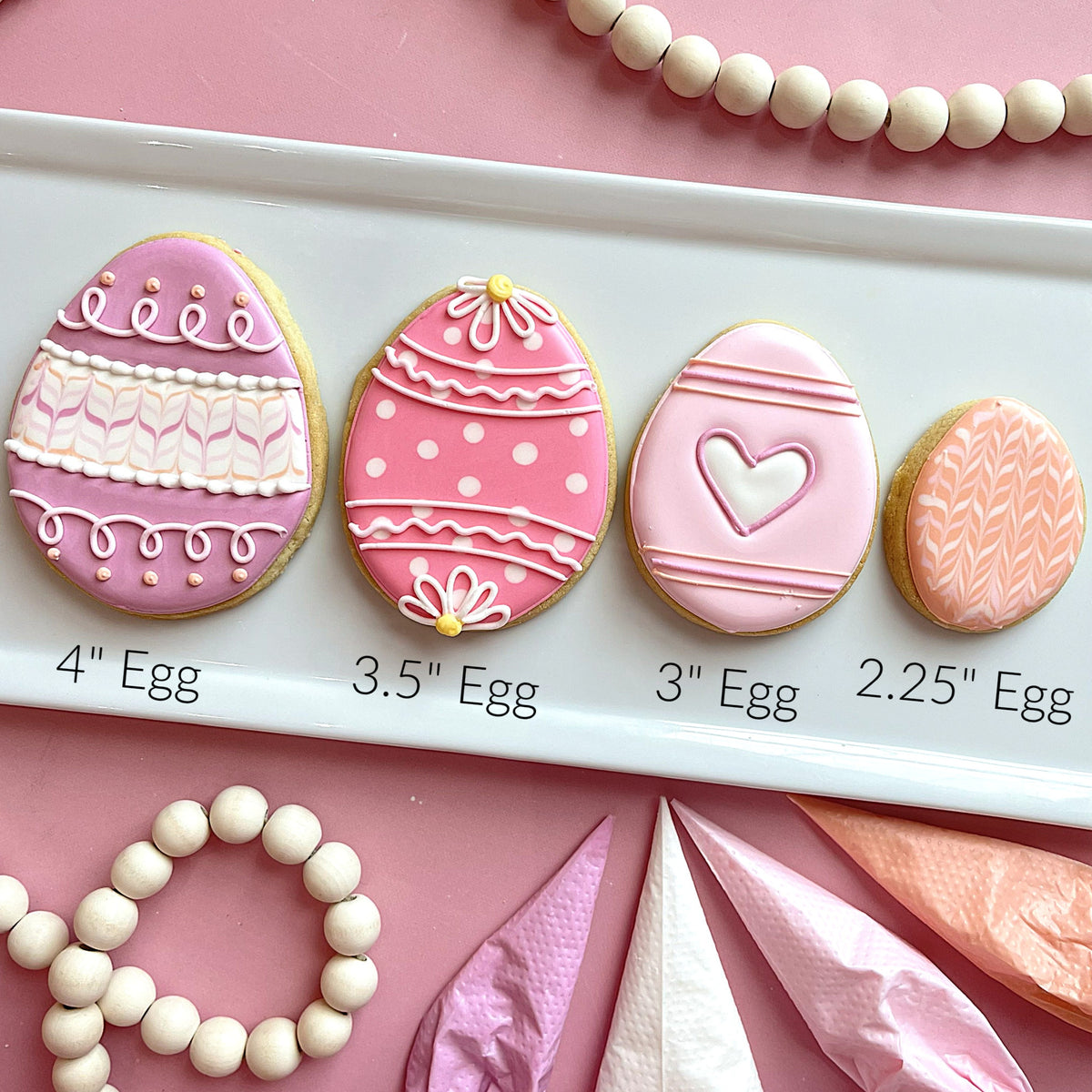 Four pink and white intricately decorated sugar cookies shaped like easter eggs made with mini 2.25 inch egg cookie cutter