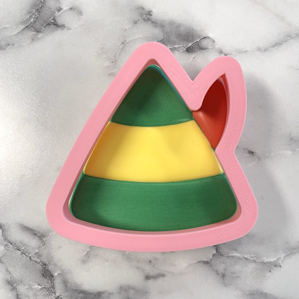 Pink plastic elf hat cookie cutter with green yellow and red stripes for holiday baking and decorating