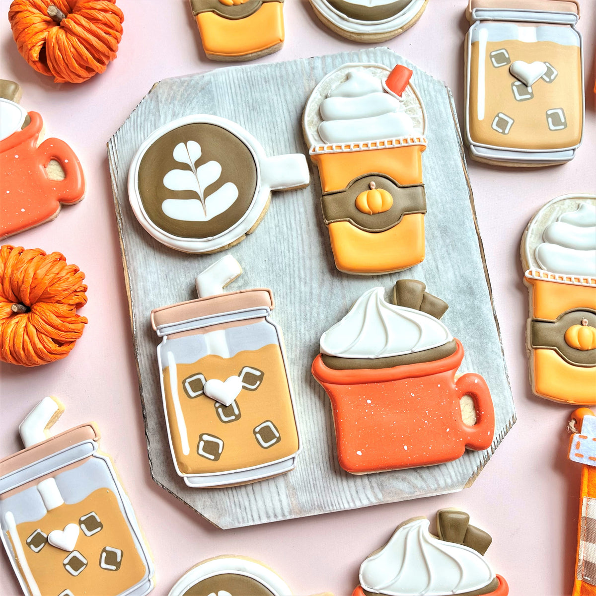 Campfire mug cookie cutter shaped orangish-orange frosted pumpkin spice latte cookie with white icing swirls and brown accents