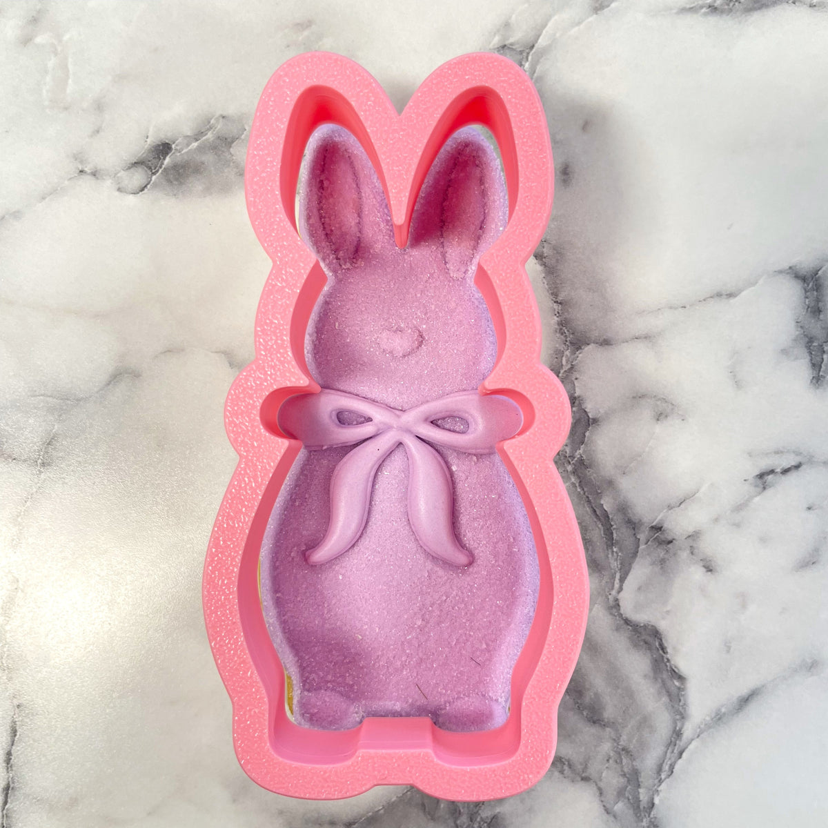 Pink silicone flocked bunny with bow cookie cutter mold filled with glittery lavender soap featuring molded ears and bow