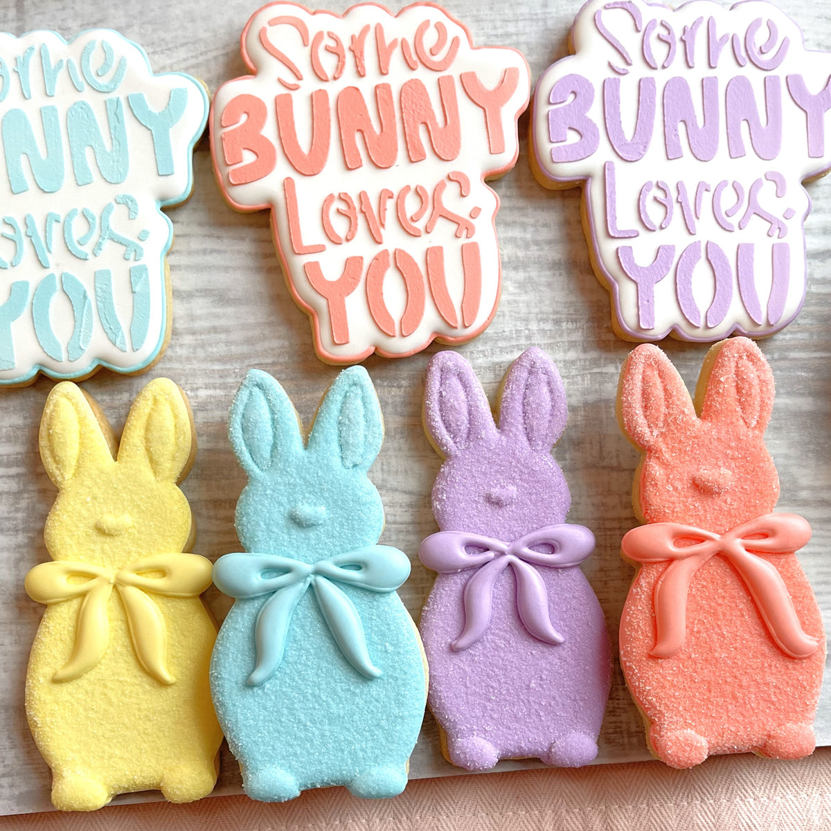 Pastel-colored bunny-shaped sugar cookies with decorative bows made using some bunny loves you cookie cutter bundle