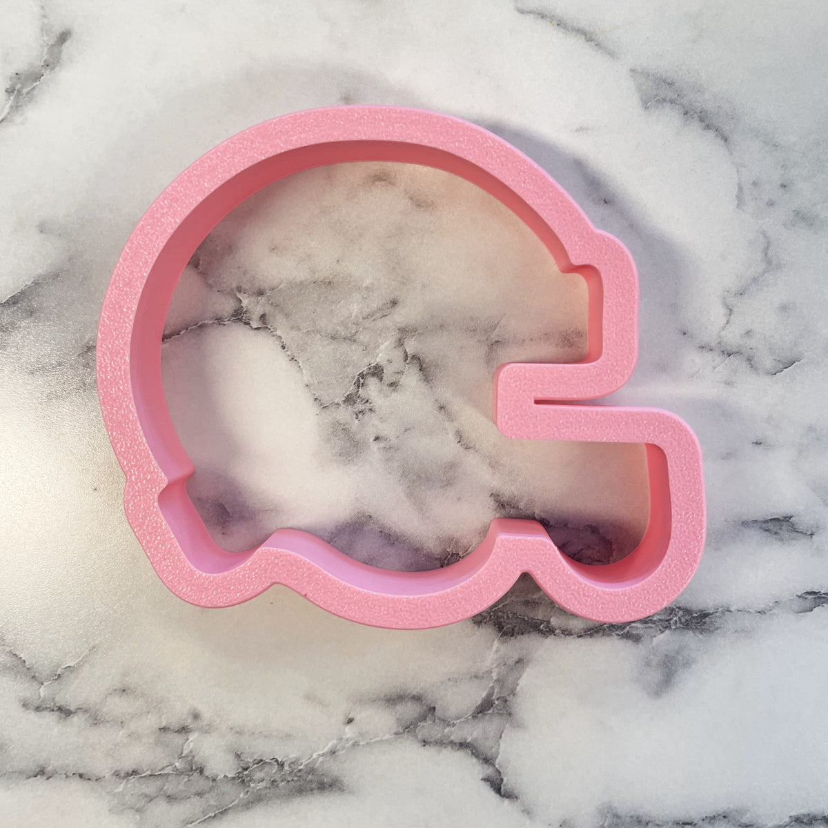 Pink glittery football helmet cookie cutter made of metal for baking and decorating themed cookies