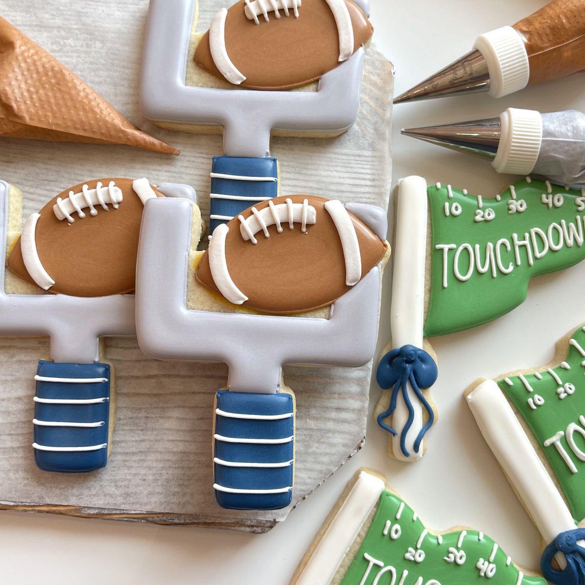 Brown football-shaped sugar cookies with white icing laces decorated on a gray goalpost cookie football cookie cutter bundle