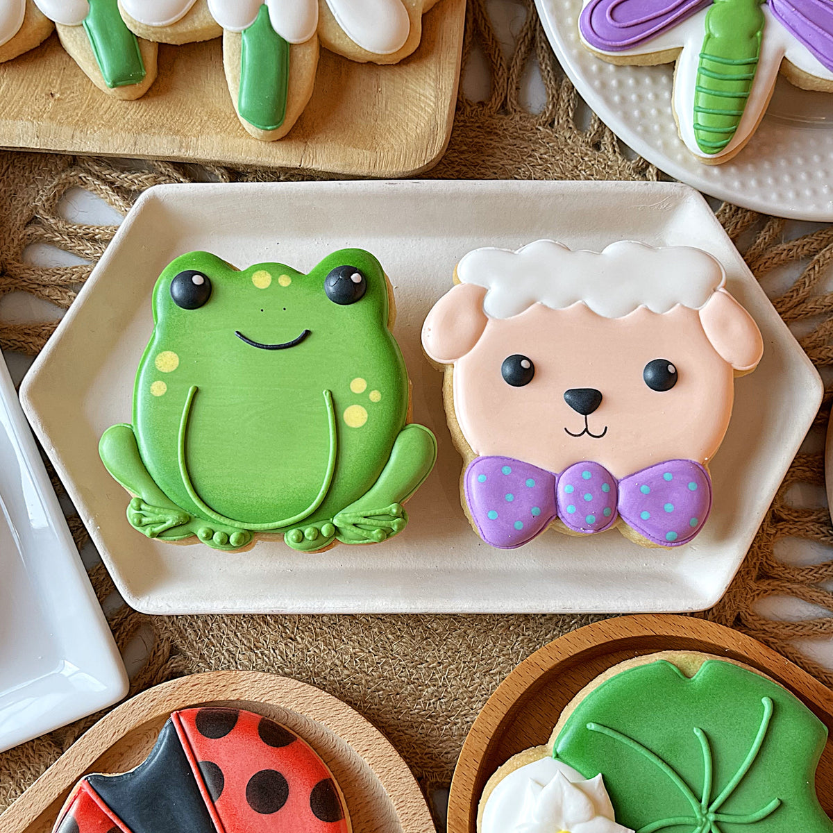Cute frog and pink lamb shaped cookies with yellow spots and bow tie made using flour box club flip cookie cutter