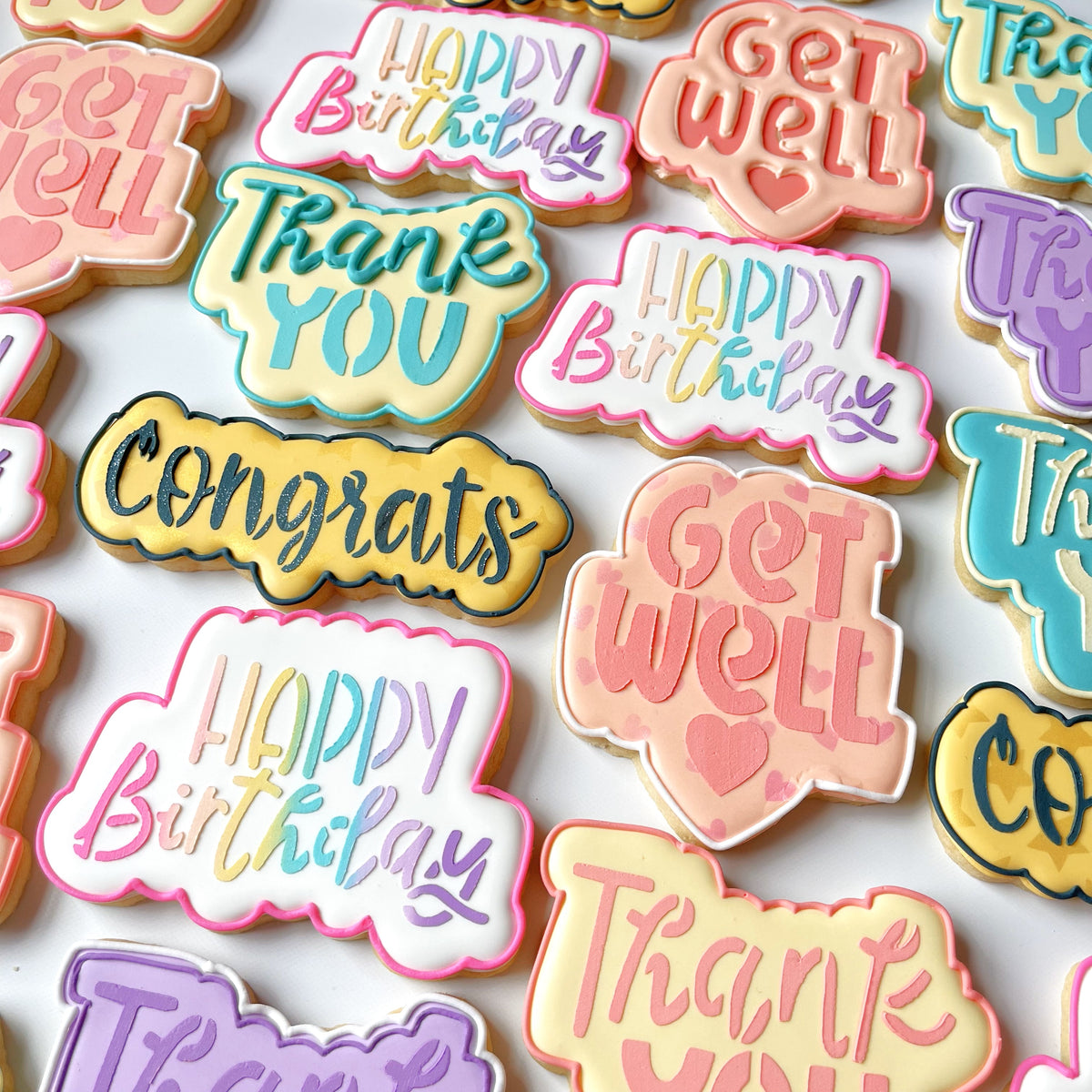 Pastel-colored sugar cookies shaped like speech bubbles with get well messages made using cookie cutter and stencil set
