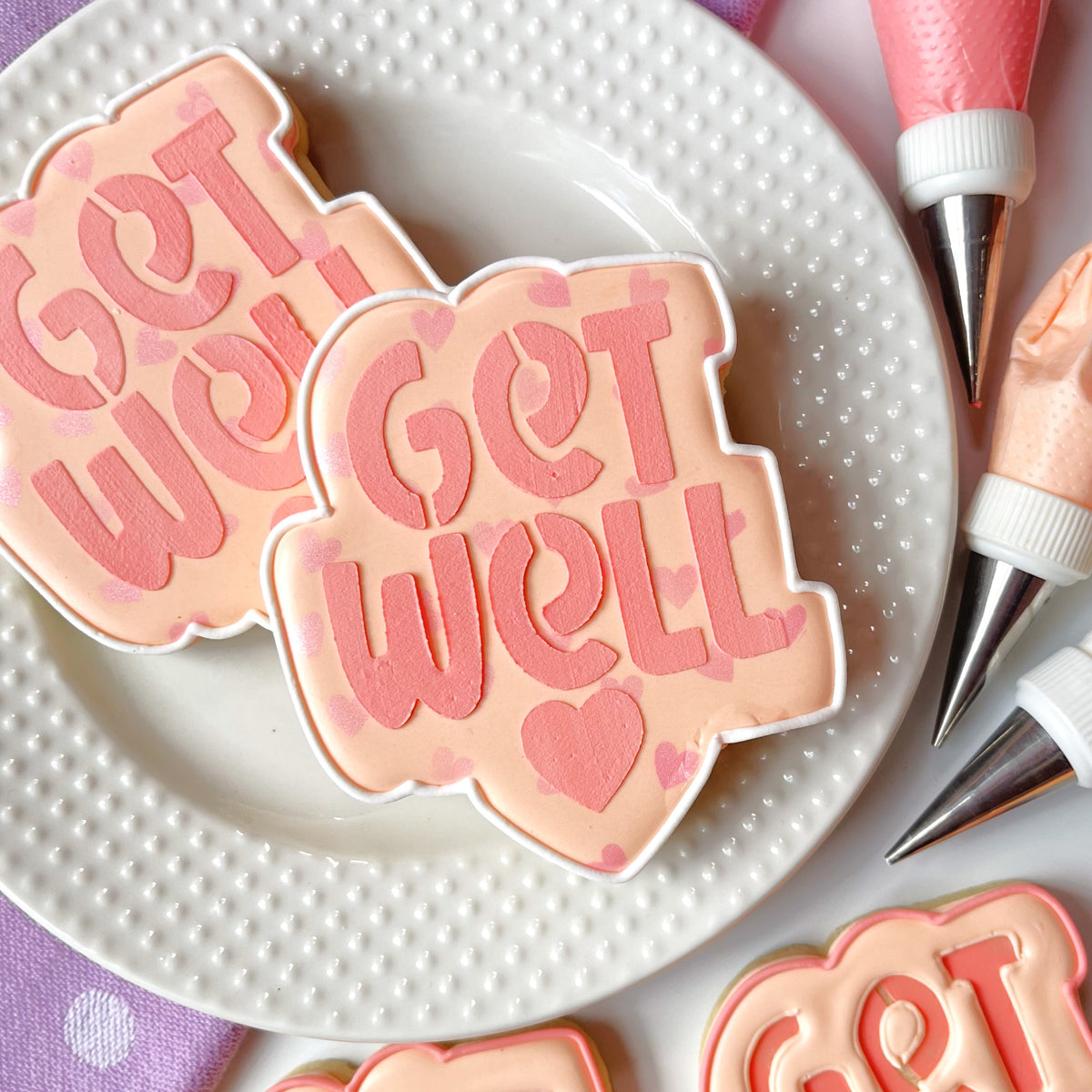 Pastel pink and white get well sugar cookies with heart decorations made using cookie cutter and stencil set