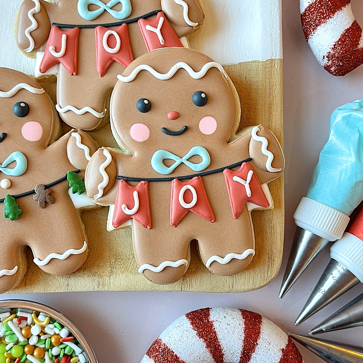Gingerbread boy with banner cookie cutter shaped like a gingerbread man with brown icing and red joy banners