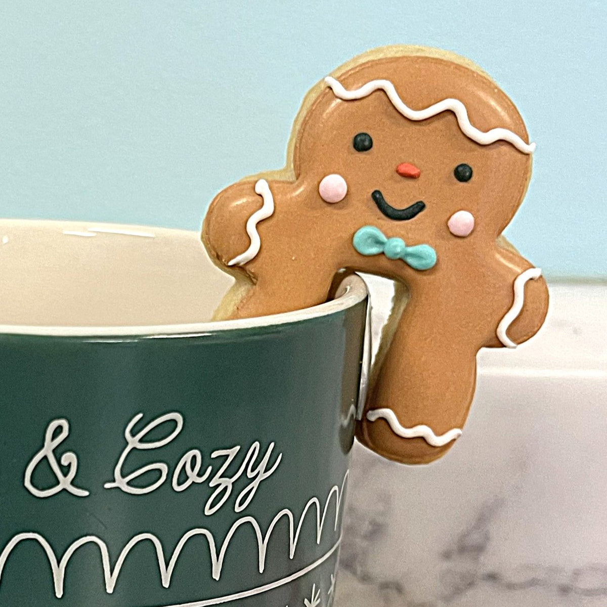 Mini gingerbread man mug hugger cookie cutter with brown gingerbread design white icing trim and turquoise bow tie