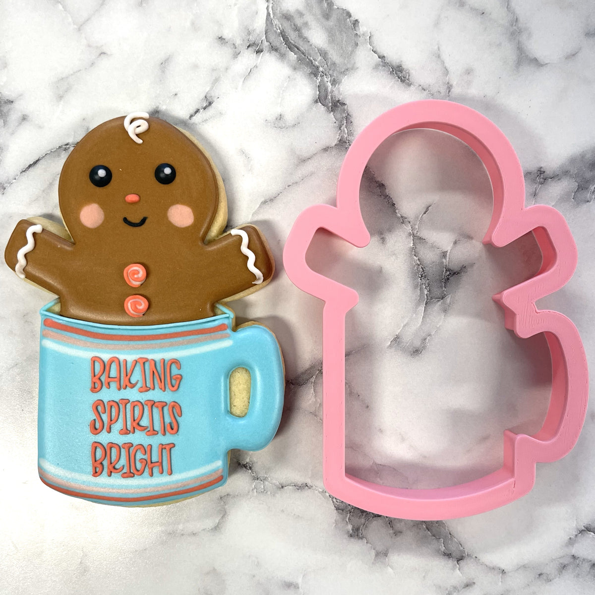 A brown gingerbread man cookie with rosy cheeks inside a light blue mug cookie cutter reading baking spirits bright