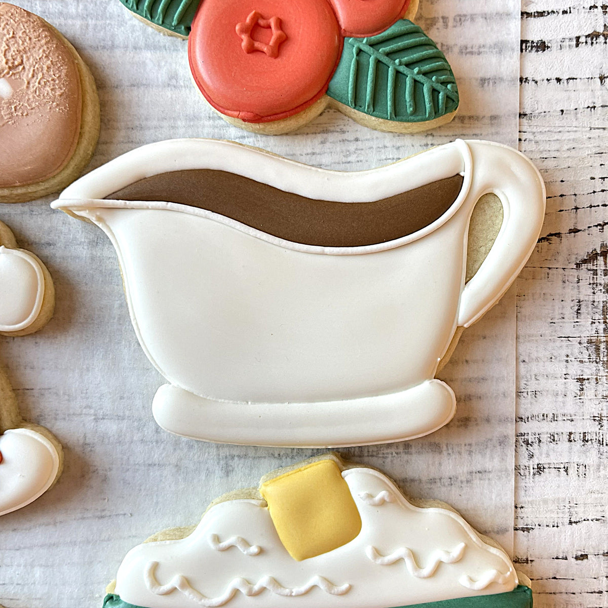 White icing covered sugar cookie shaped like a gravy boat with brown icing from turkey dinner cookie cutter bundle