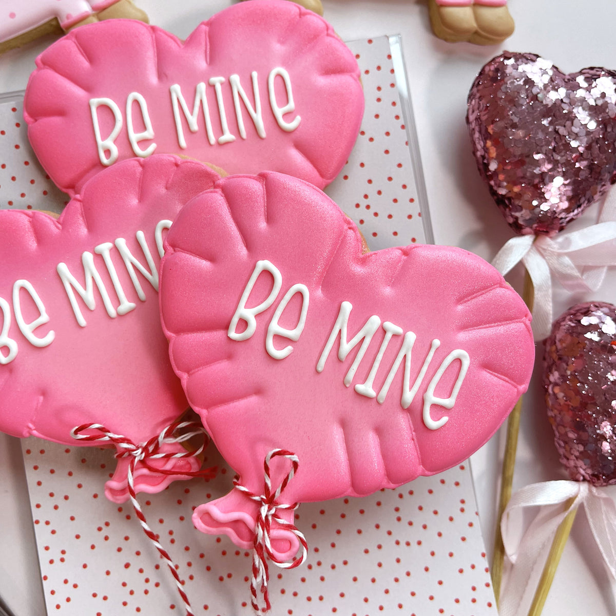 Pink heart-shaped cookies with white be mine icing tied with red and white twine from dachshund valentine cookie cutter bundle