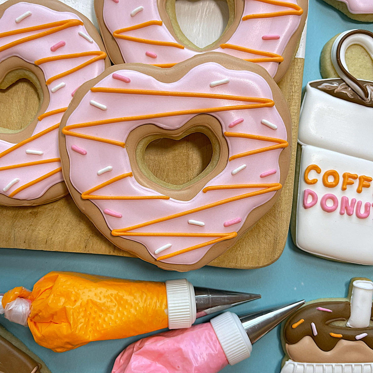 Pink heart-shaped donut cookie with pink and orange icing and white and pink sprinkles for donut online class recording