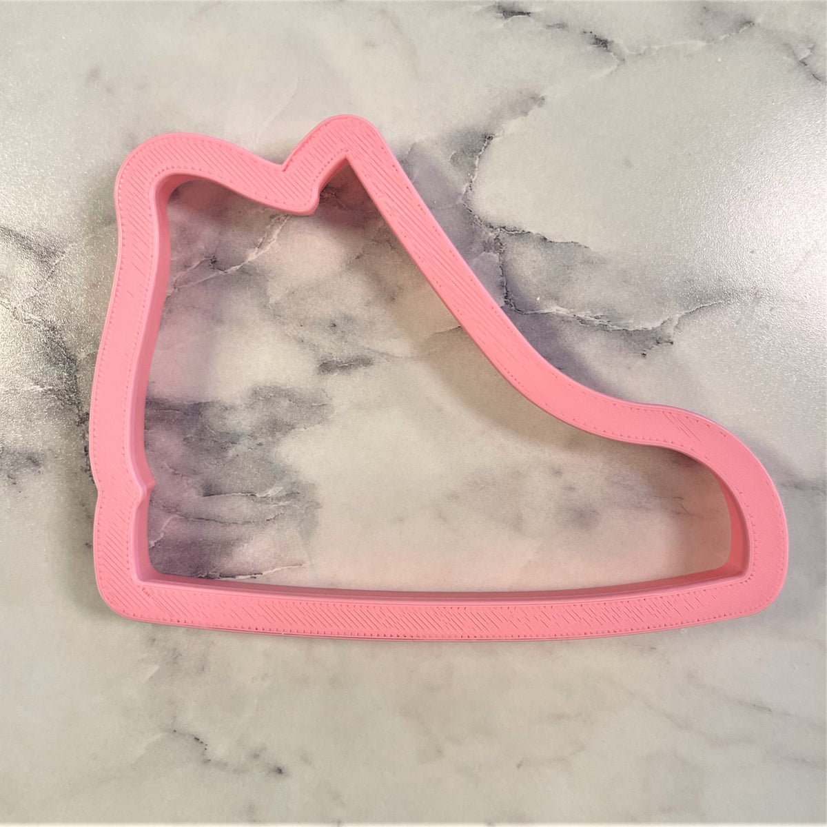 Pink plastic high top sneaker cookie cutter shaped like an ice skate for baking and decorating cookies