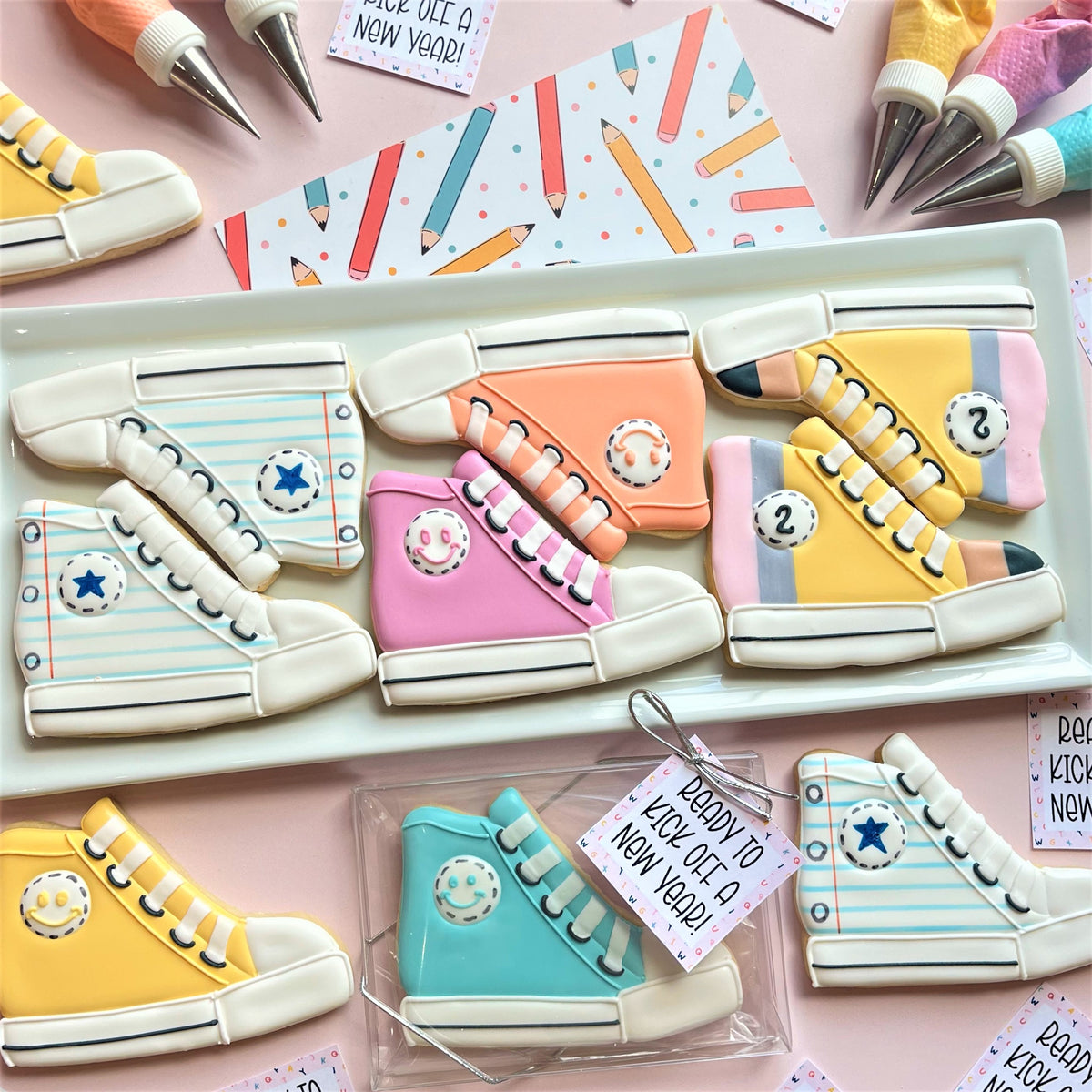 Pastel-colored high top sneaker-shaped sugar cookies with icing details and smiley face accents made using high top sneaker cookie cutter