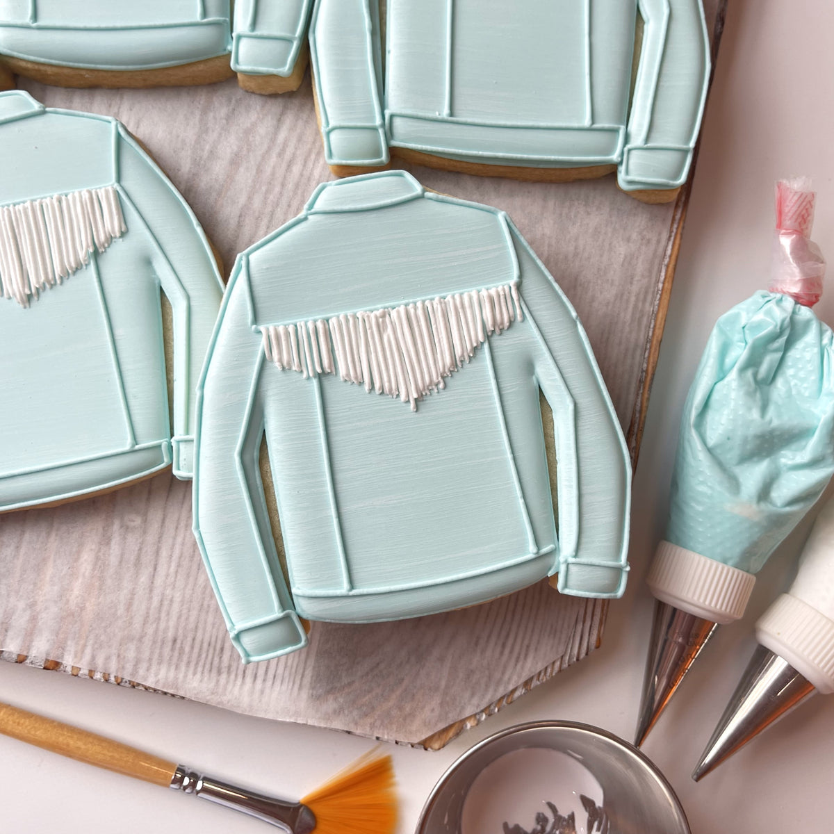 Light blue frosted western jacket cookie with white icing fringe detail from western cutter with stencil bundle