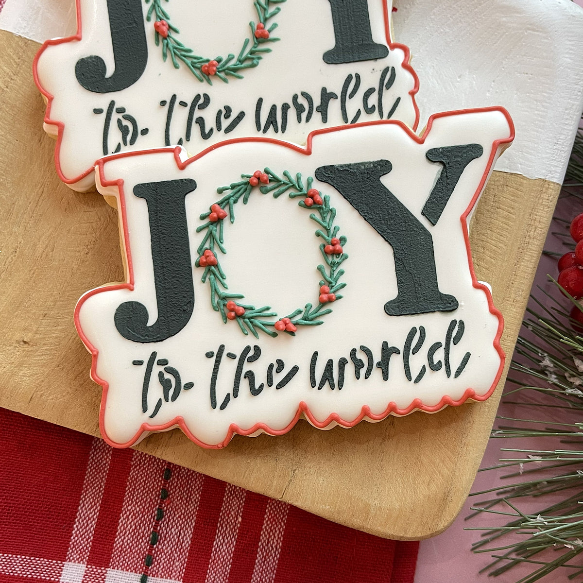 Holiday winter 2025 cookie cutter set white frosted joy cookie with black icing and green wreath with red berries and pink border