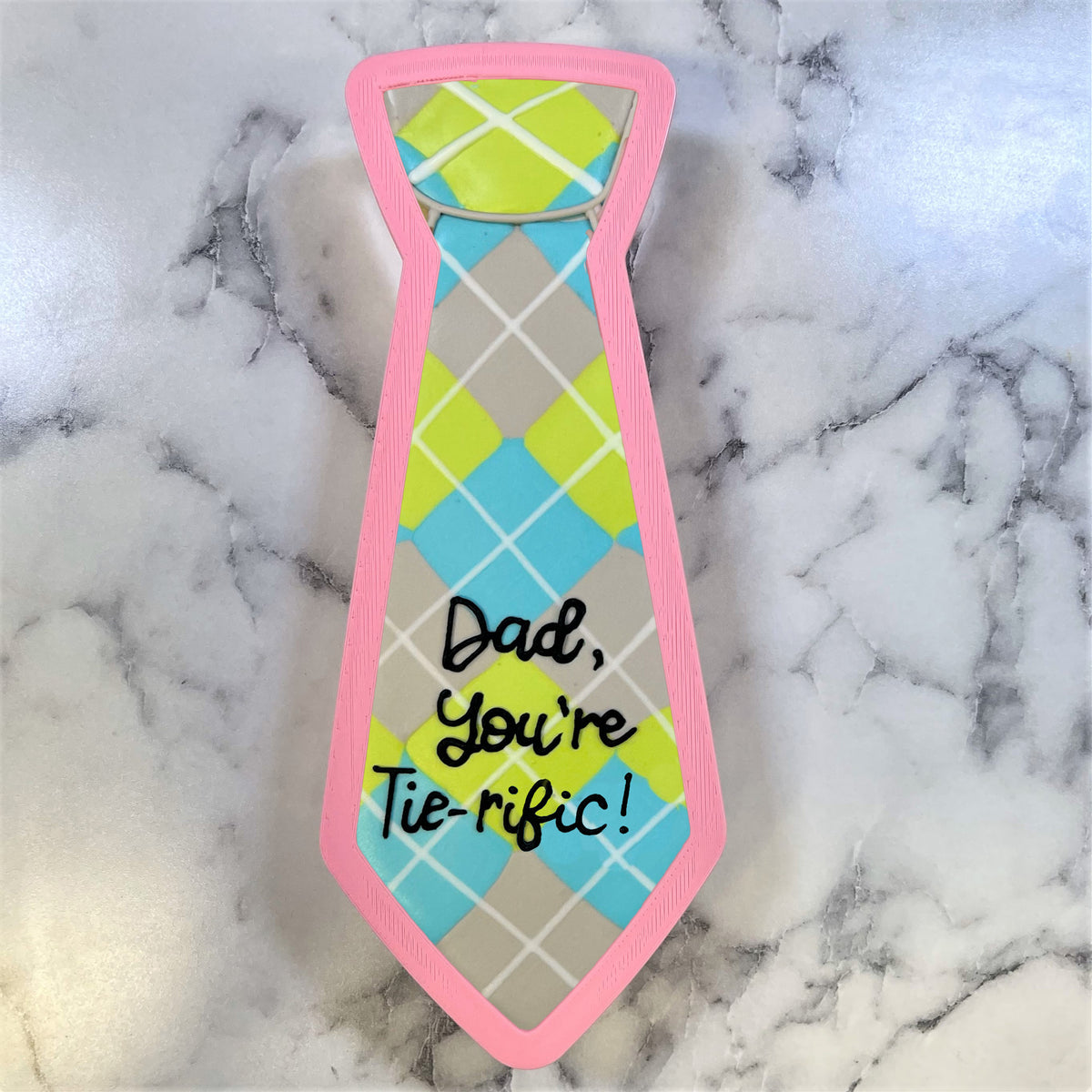 Jumbo tie cookie cutter shaped cookie with pink edges and lime green light blue gray argyle pattern and dad youre tieric text