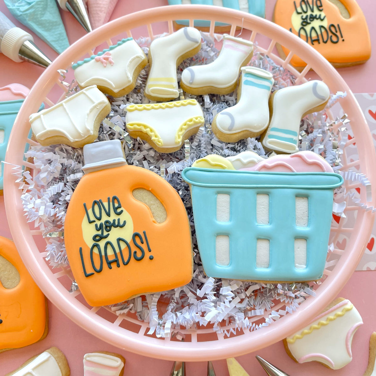 Orange sugar cookie shaped like a laundry detergent bottle with love you loads icing made using laundry detergent cookie cutter