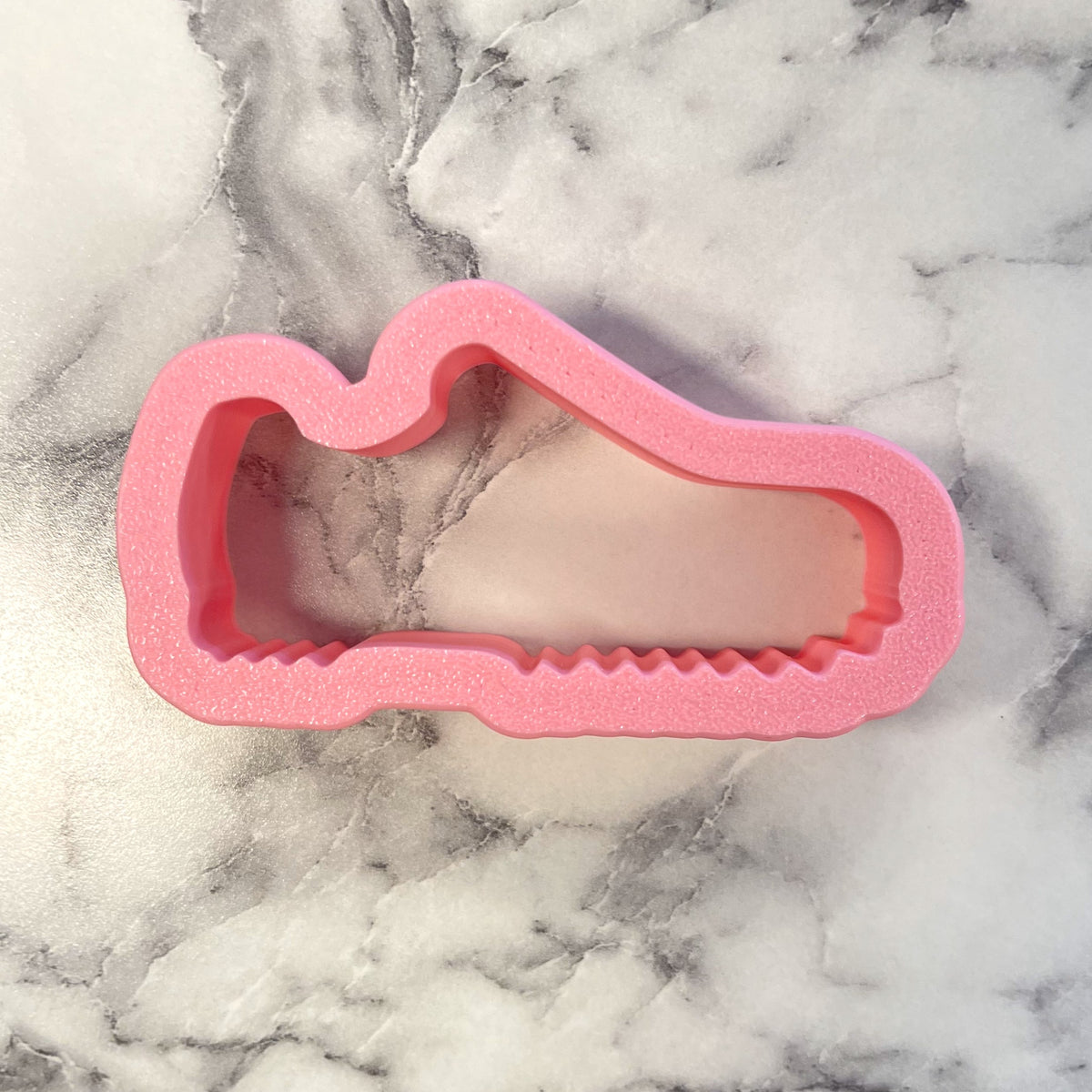 Pink foam mini golf shoes cookie cutter shaped like a sneaker for baking and decorating cookies