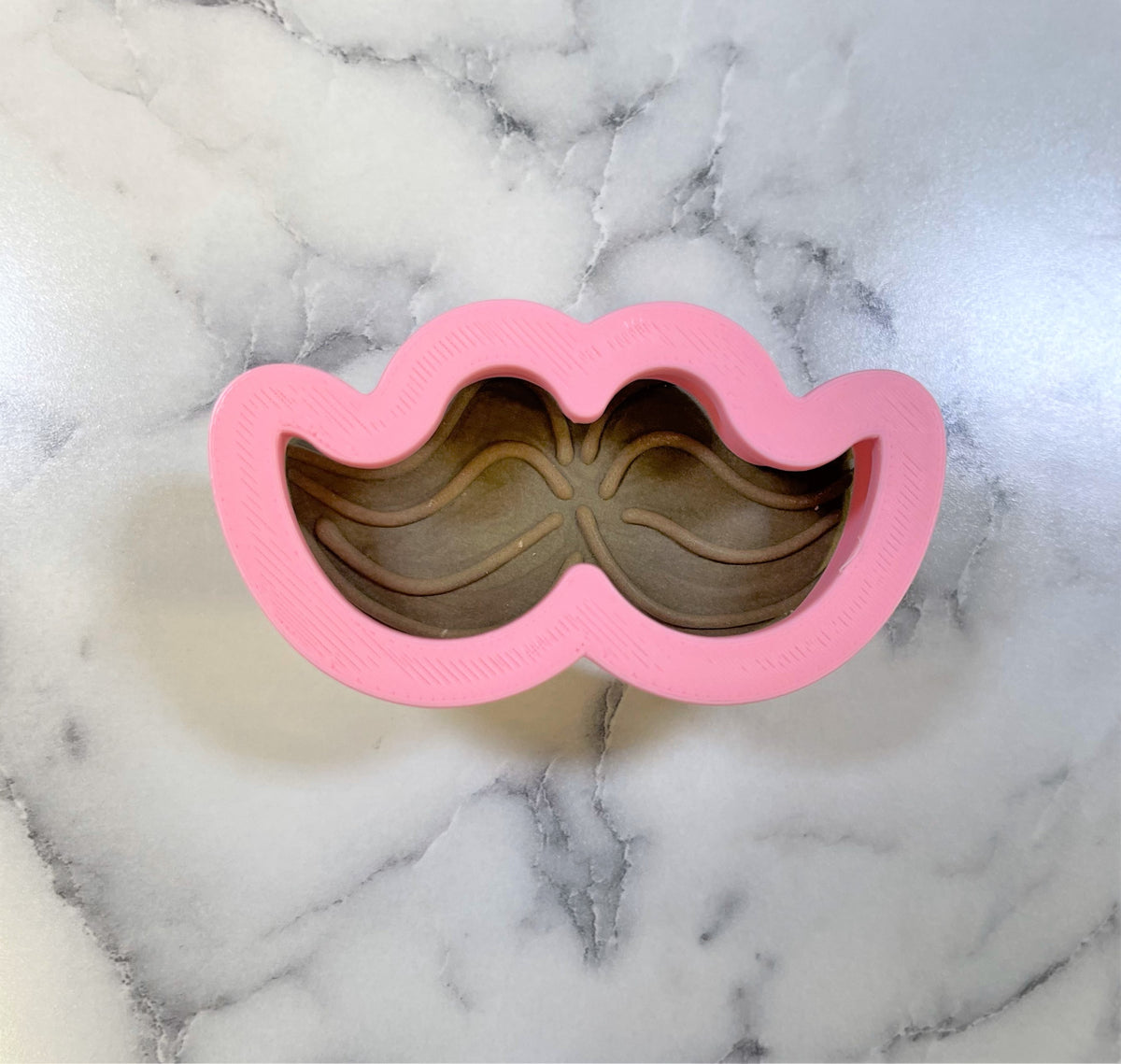 Mini mustache cookie cutter made of pink silicone for shaping small mustache cookies