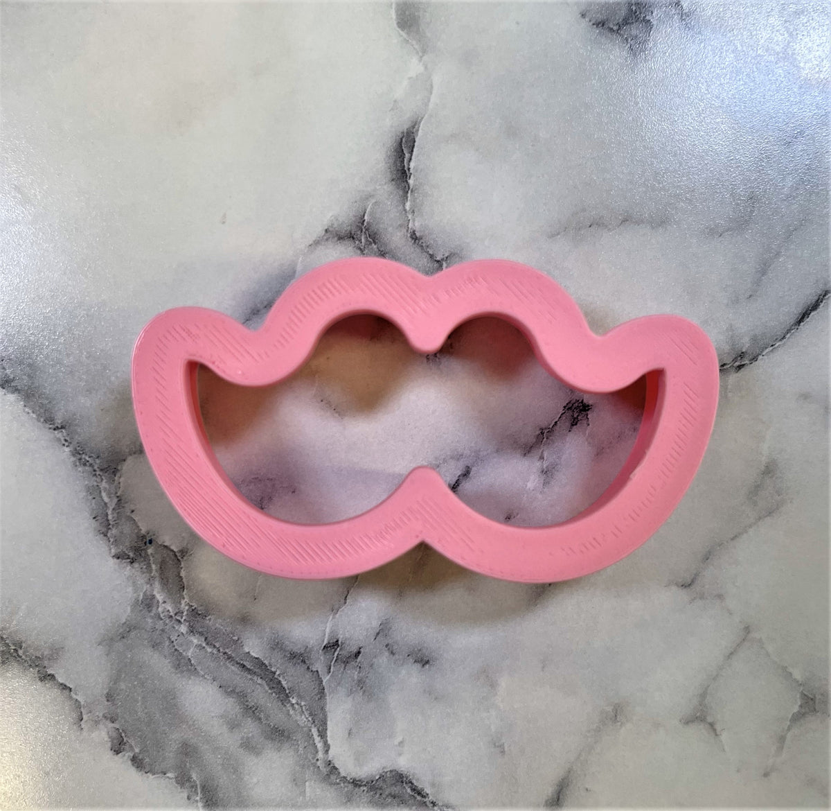 Pink silicone mini mustache cookie cutter designed for baking and shaping small cookies and treats