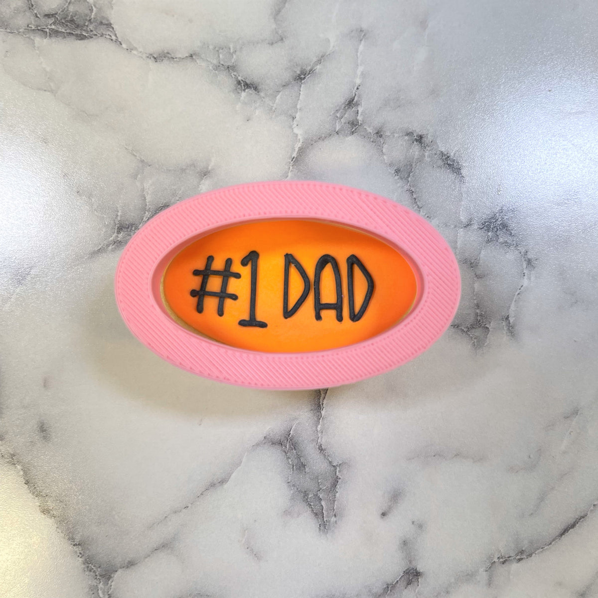 Mini oval cookie cutter pink oval shaped with vibrant orange interior and black #1 dad text for baking use