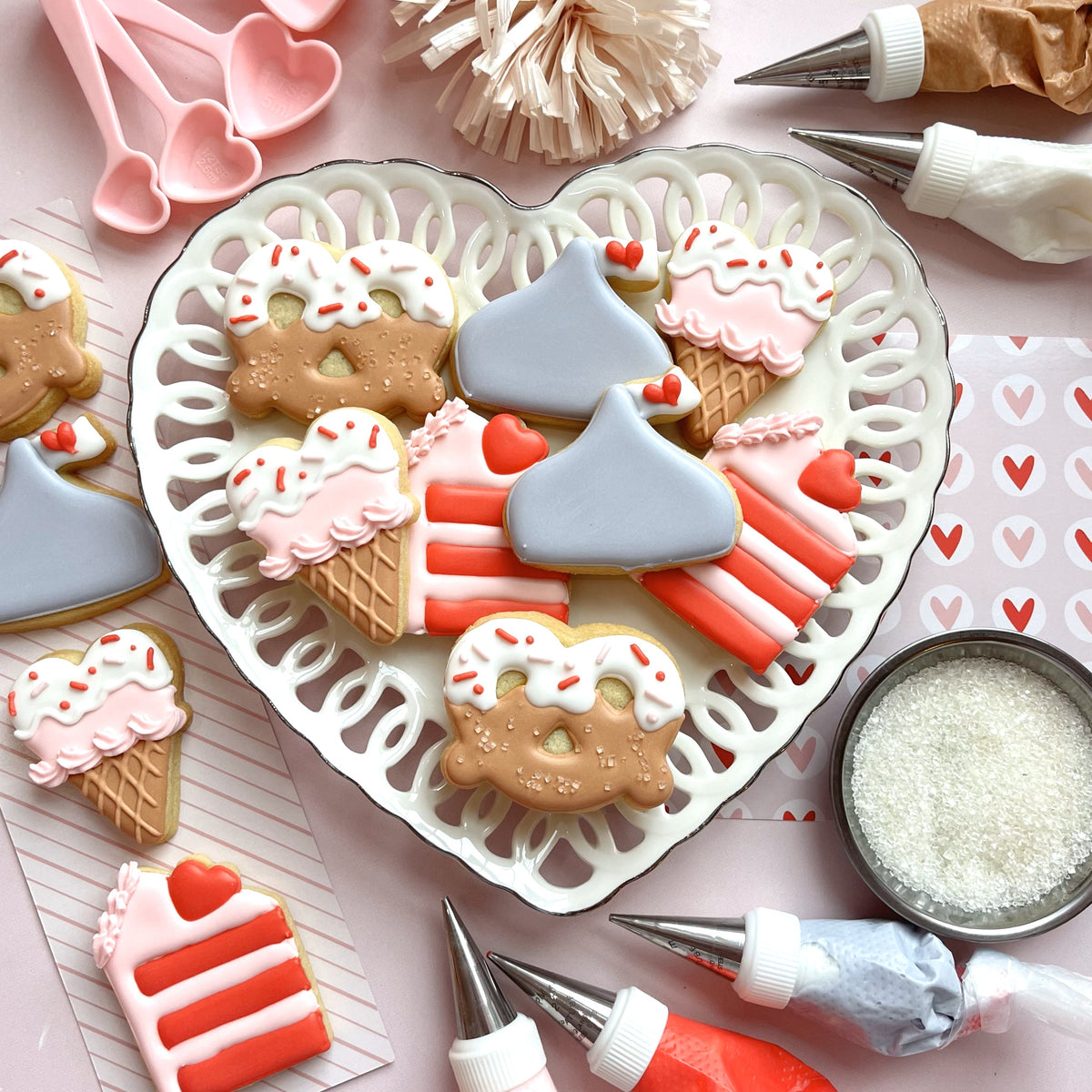 Heart-shaped white lace plate holding intricately decorated valentine’s day cookies from mini valentine treats cookie cutter bundle